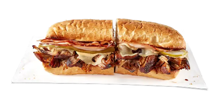 A flavorful Potbelly Menu item featuring a toasted sub roll filled with slow-cooked pulled pork, hickory smoked ham, melted Swiss cheese, deli mustard, and pickles, cut into portions and served on white paper against a black background, priced at $11.29 with 663 calories.