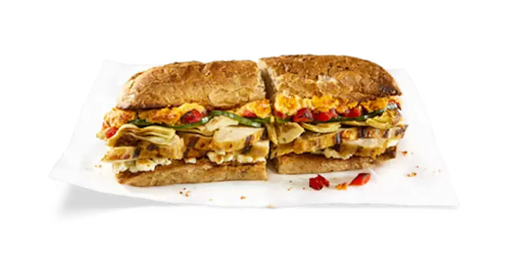A vibrant Potbelly Menu item, the Mediterranean, featuring a toasted sub roll filled with all-natural grilled chicken, creamy feta cheese, zesty hummus, tender artichoke hearts, roasted red peppers, and crisp cucumbers, cut into portions and served on white paper against a black background, priced at $12.29 with 621 calories (can be made vegetarian).