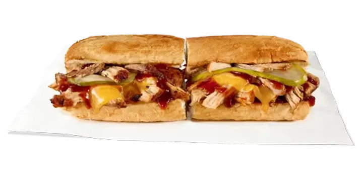 A savory Potbelly Menu item, the Sweet Heat Pork BBQ, featuring a toasted sub roll filled with slow-cooked pulled pork, melted cheddar cheese, pickles, and a sweet heat BBQ sauce made with signature hot peppers, cut into portions and served on white paper against a black background, priced at $11.49 with 753 calories.