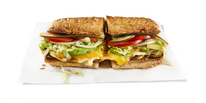 A delicious Potbelly Menu item, the Veggie Melt, featuring a toasted sub roll filled with fresh-sliced avocado, melted Swiss, cheddar, and provolone cheeses, sautéed mushrooms, crisp lettuce, tomatoes, and pickles, cut into portions and served on white paper against a black background, priced at $11.29 with 465 calories.
